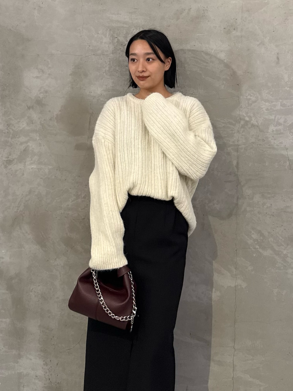 ホワイト系のニット/セーター、ブラック系のスカート、レッド系のトートバッグを着用したレディースの秋コーディネートの4枚目の写真