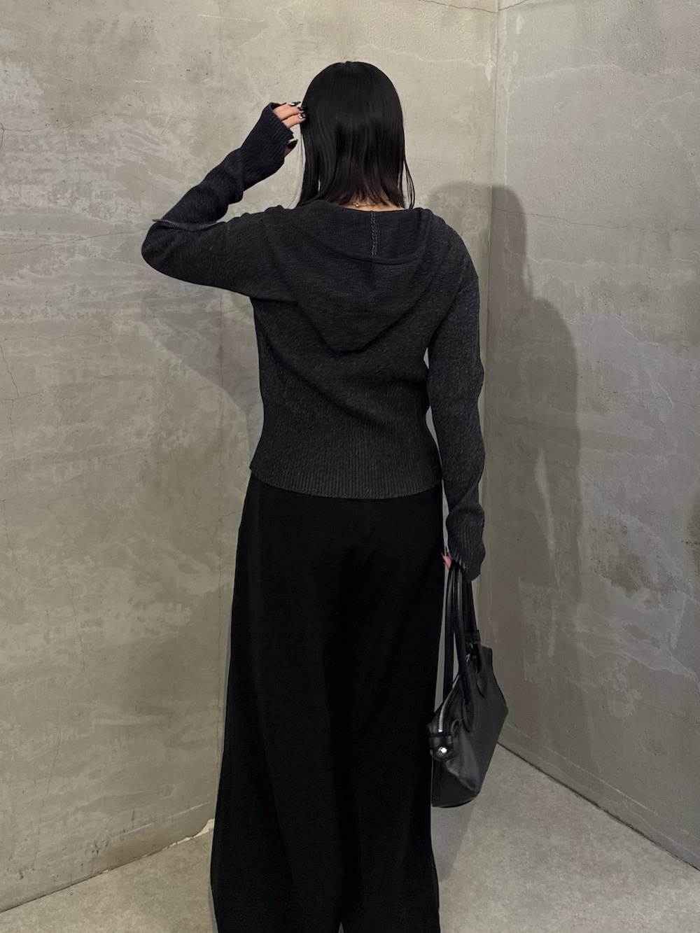 ブラック系のニット/セーター、ブラック系のスラックス、ブラック系のトートバッグを着用したレディースの冬コーディネートの4枚目の写真