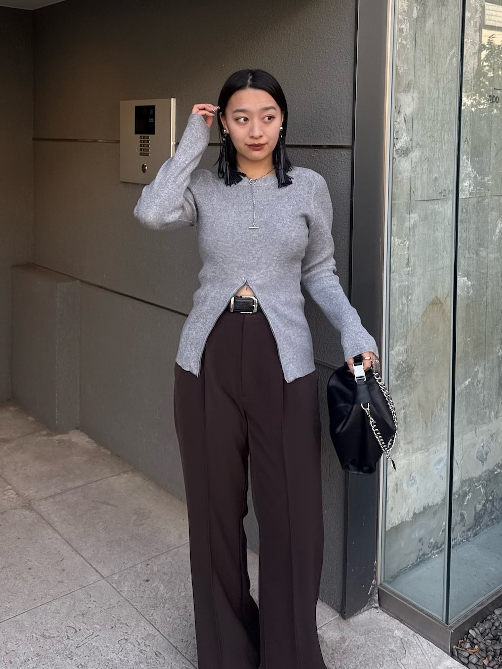 グレー系のニット/セーター、ブラウン系のスラックス、ブラック系のトートバッグを着用したレディースの冬コーディネートの3枚目の写真