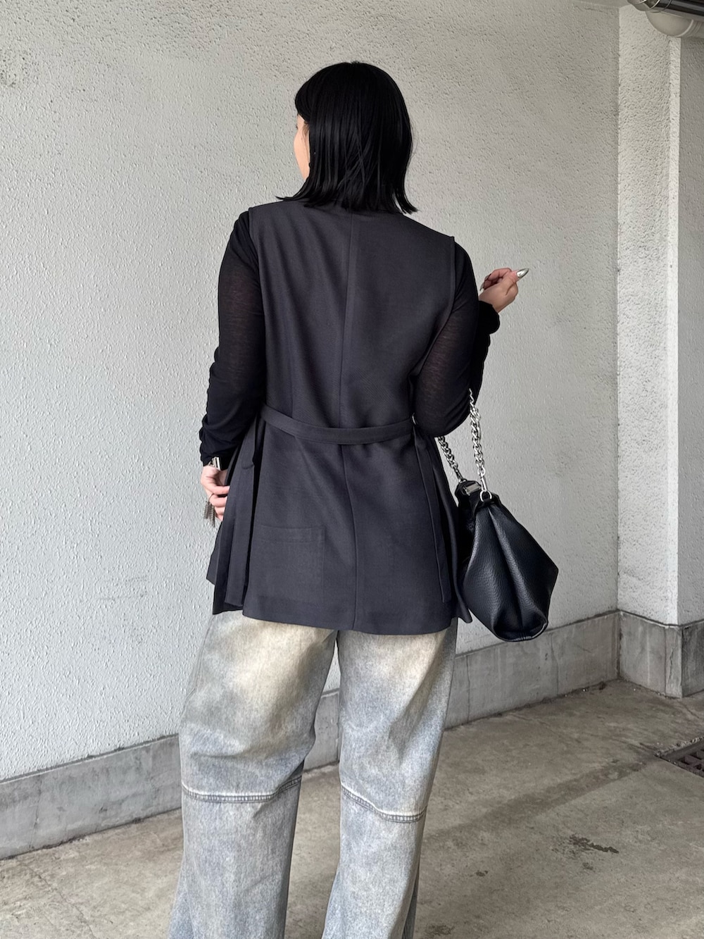 グレー系のベスト、ブラック系のTシャツ/カットソー、ブラック系のデニムパンツを着用したレディースの春コーディネートの5枚目の写真