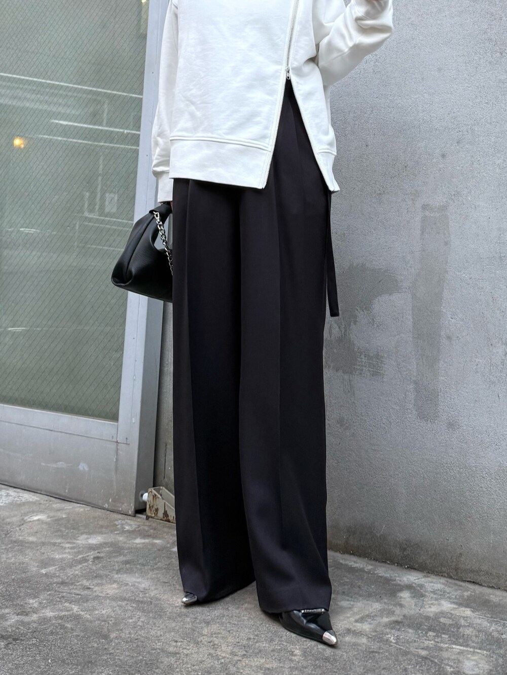 ホワイト系のTシャツ/カットソー、ブラック系のスラックス、ブラック系のトートバッグを着用したレディースの冬コーディネートの6枚目の写真