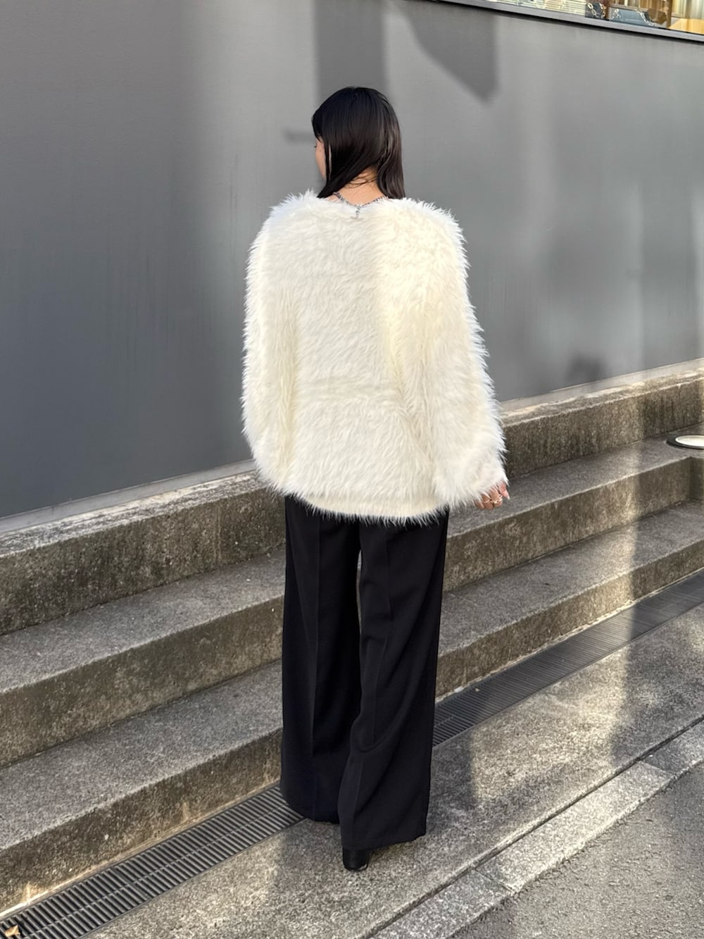 ブラック系のスラックス、ブラック系のブーツ、ホワイト系のカーディガン/ボレロを着用したレディースの夏コーディネートの2枚目の写真