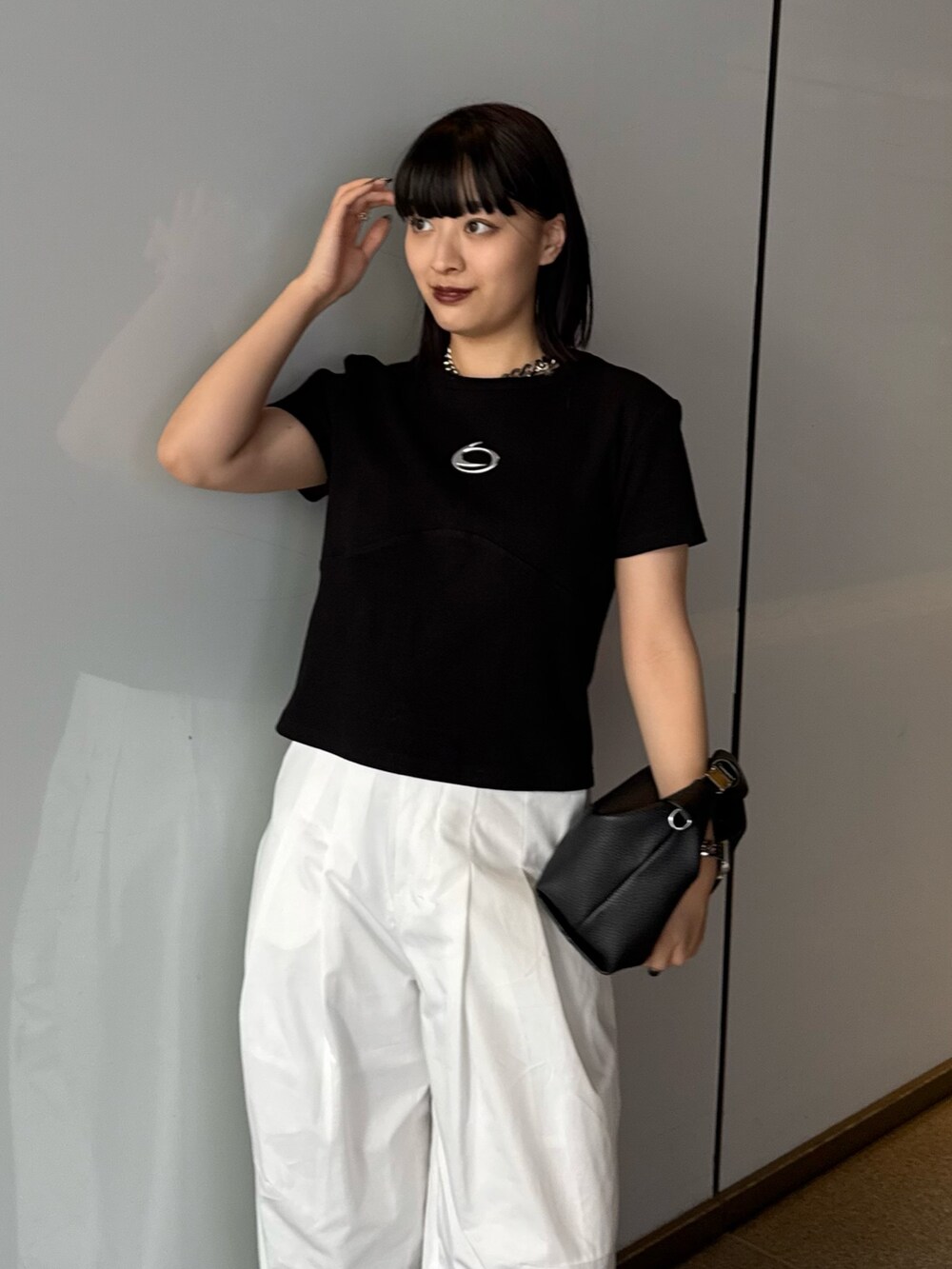 ブラック系のTシャツ/カットソー、ホワイト系のスラックス、ブラック系のショルダーバッグを着用したレディースの春コーディネートの4枚目の写真