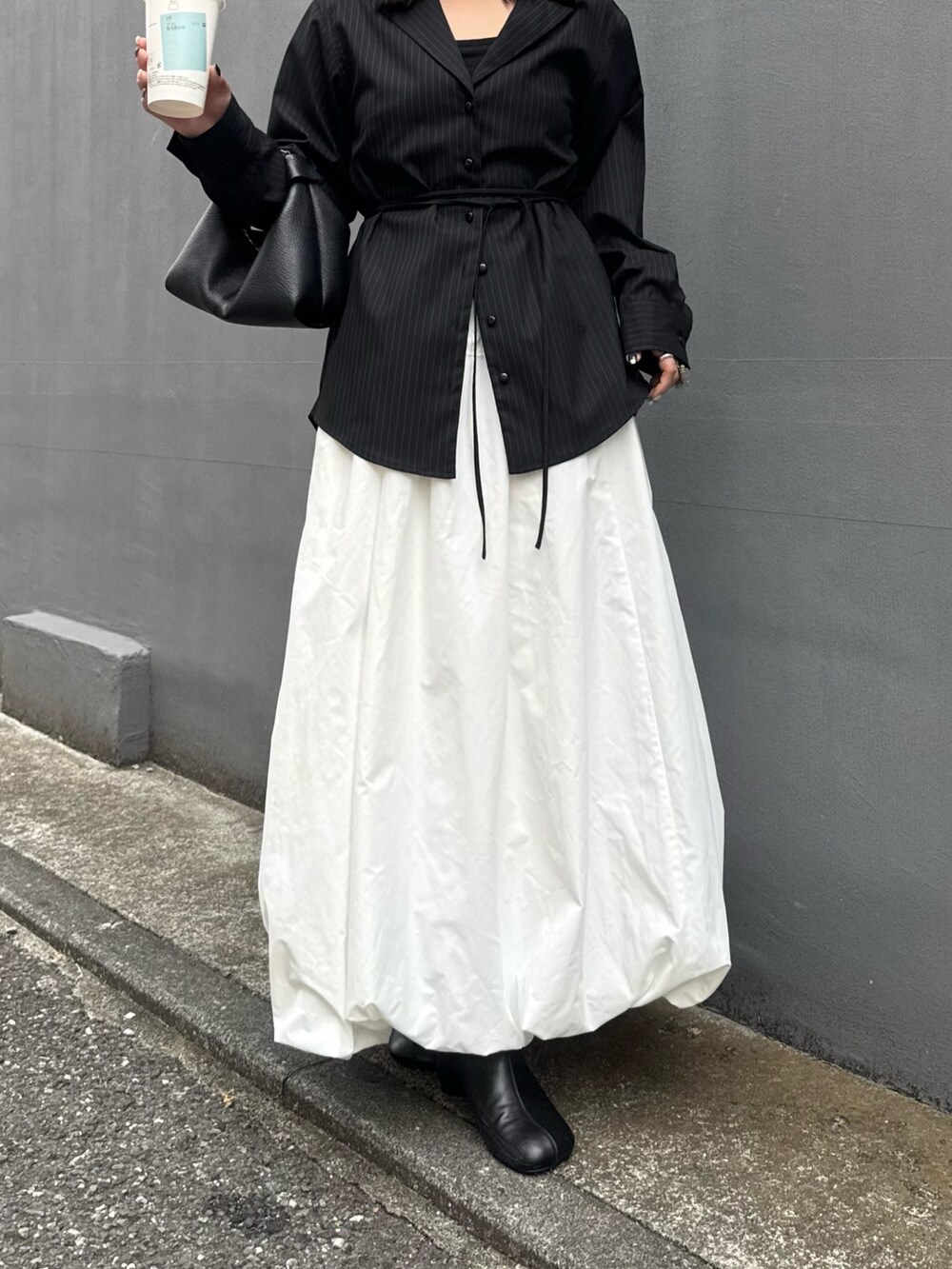 グレー系のシャツ/ブラウス、ホワイト系のスカート、ブラック系のトートバッグを着用したレディースの秋コーディネートの5枚目の写真