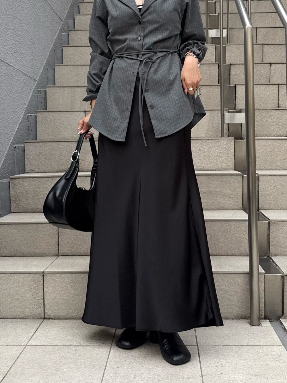 グレー系のシャツ/ブラウス、ブラック系のスカート、ブラック系のブーツを着用したレディースの夏コーディネートの5枚目の写真