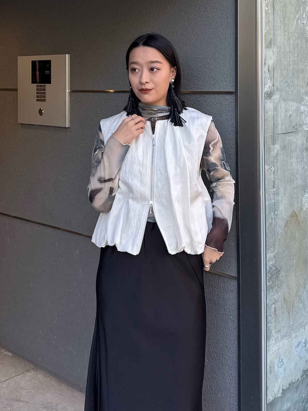 ホワイト系のベスト、グリーン系のTシャツ/カットソー、ブラック系のスカートを着用したレディースの春コーディネートの3枚目の写真