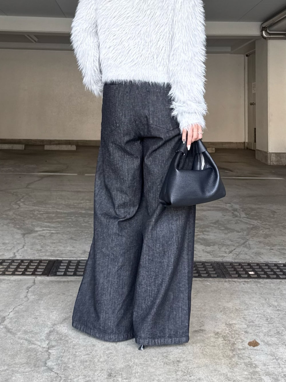 ブラック系のデニムパンツ、ブラック系のトートバッグ、グレー系のニット/セーターを着用したレディースの秋コーディネートの4枚目の写真