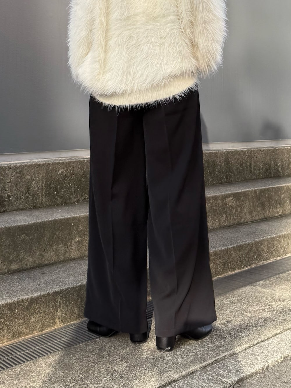 ブラック系のスラックス、ブラック系のブーツ、ホワイト系のカーディガン/ボレロを着用したレディースの夏コーディネートの6枚目の写真