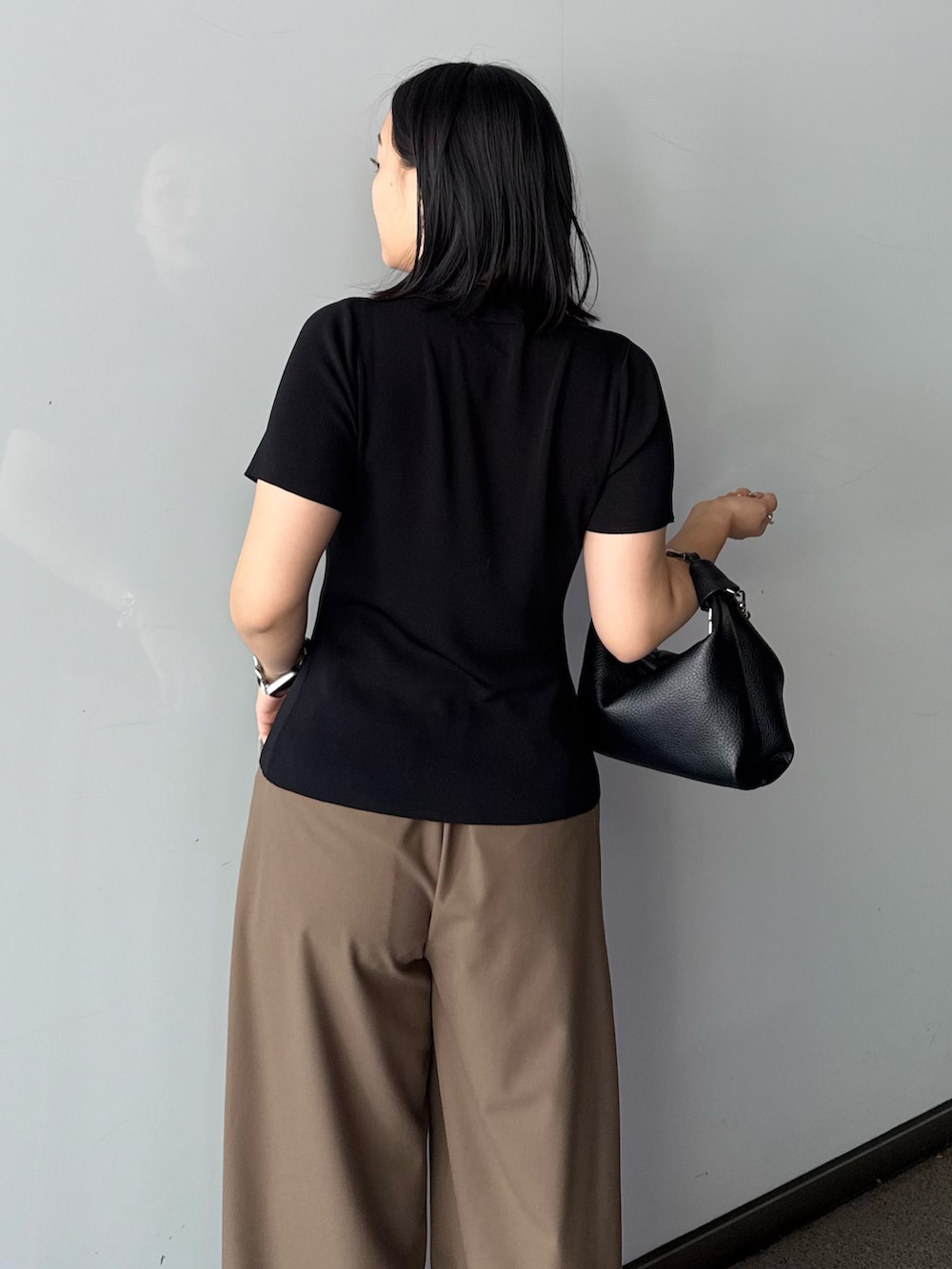 ブラック系のTシャツ/カットソー、ブラウン系のスラックス、ブラック系のトートバッグを着用したレディースの春コーディネートの4枚目の写真