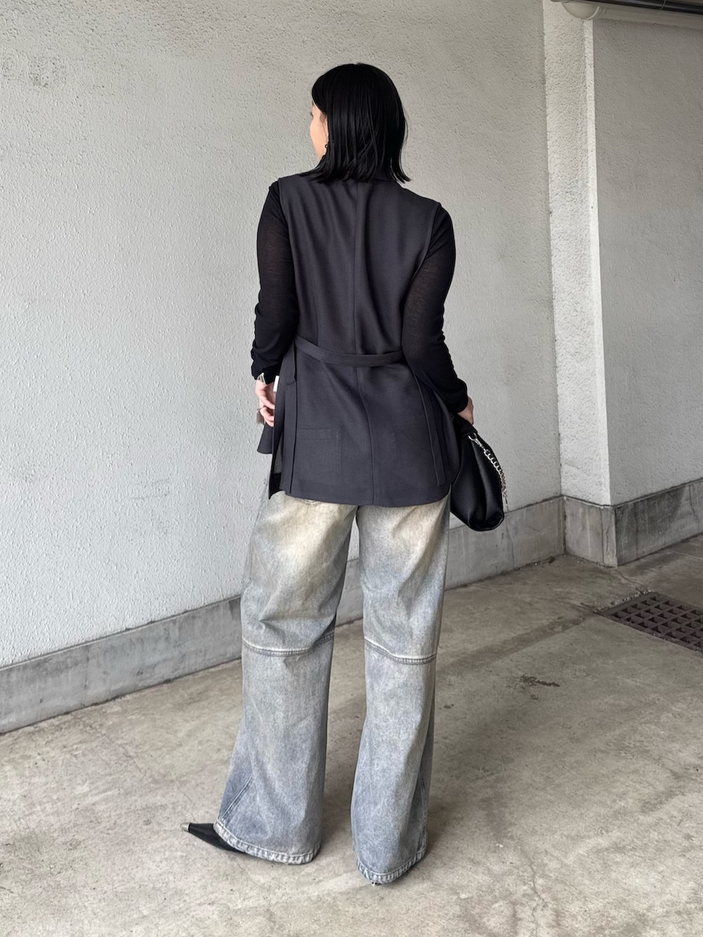 グレー系のベスト、ブラック系のTシャツ/カットソー、ブラック系のデニムパンツを着用したレディースの春コーディネートの3枚目の写真