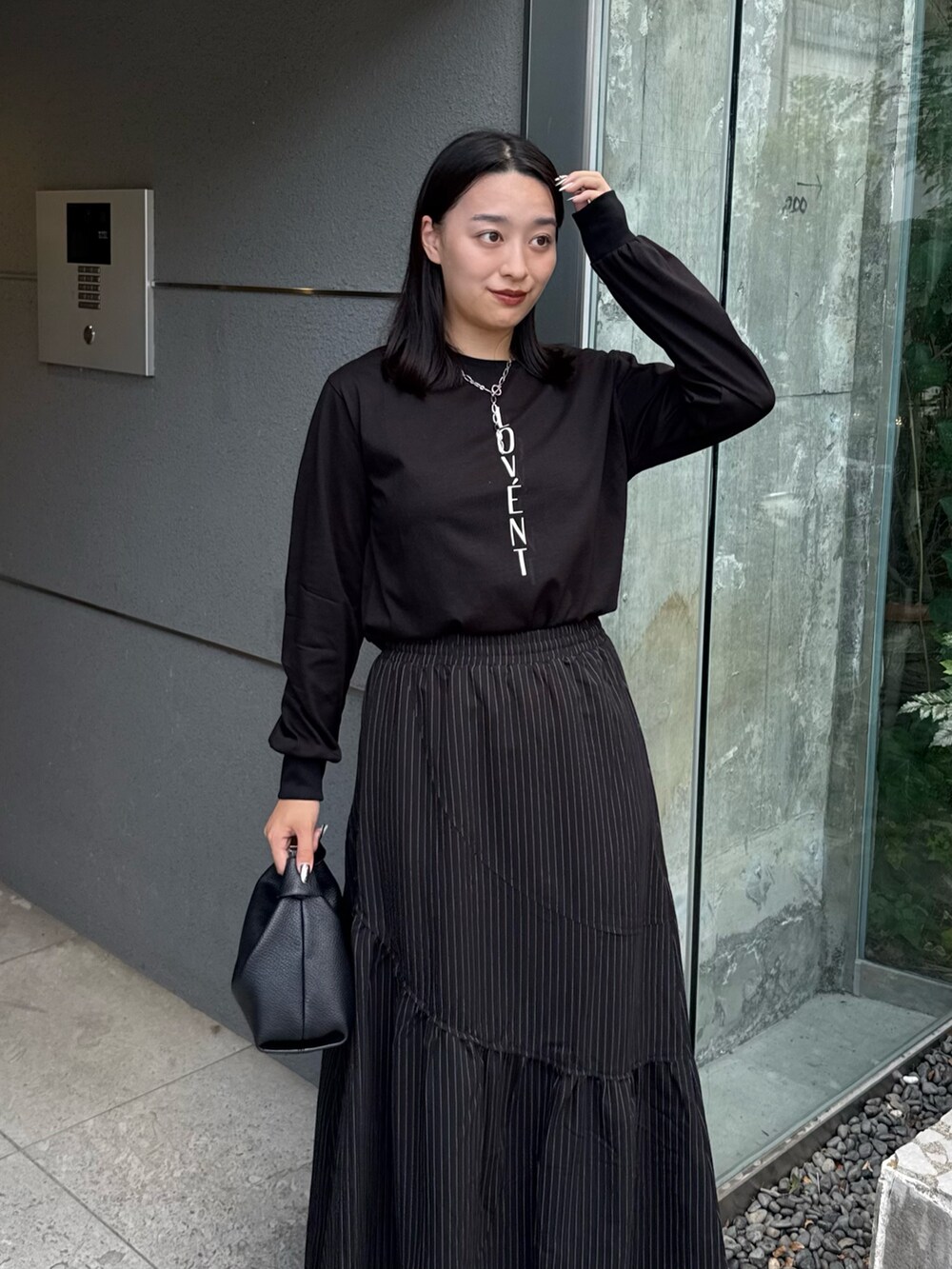 ブラック系のTシャツ/カットソー、ブラック系のスカート、ブラック系のトートバッグを着用したレディースの秋コーディネートの4枚目の写真