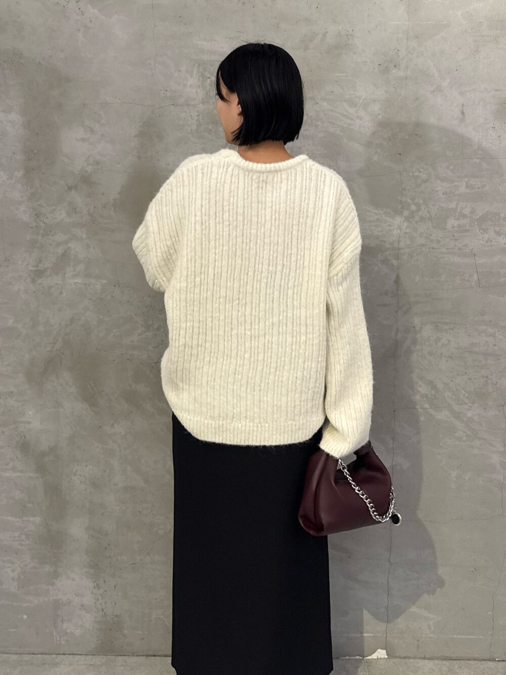 ホワイト系のニット/セーター、ブラック系のスカート、レッド系のトートバッグを着用したレディースの秋コーディネートの5枚目の写真