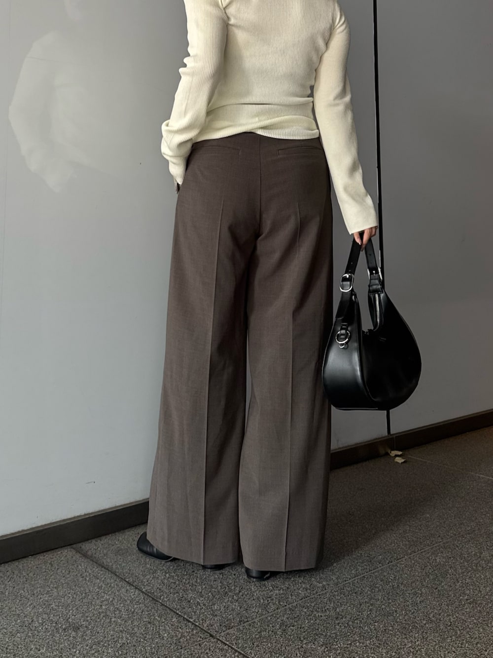 ホワイト系のニット/セーター、ブラウン系のスラックス、ブラック系のブーツを着用したレディースの夏コーディネートの5枚目の写真