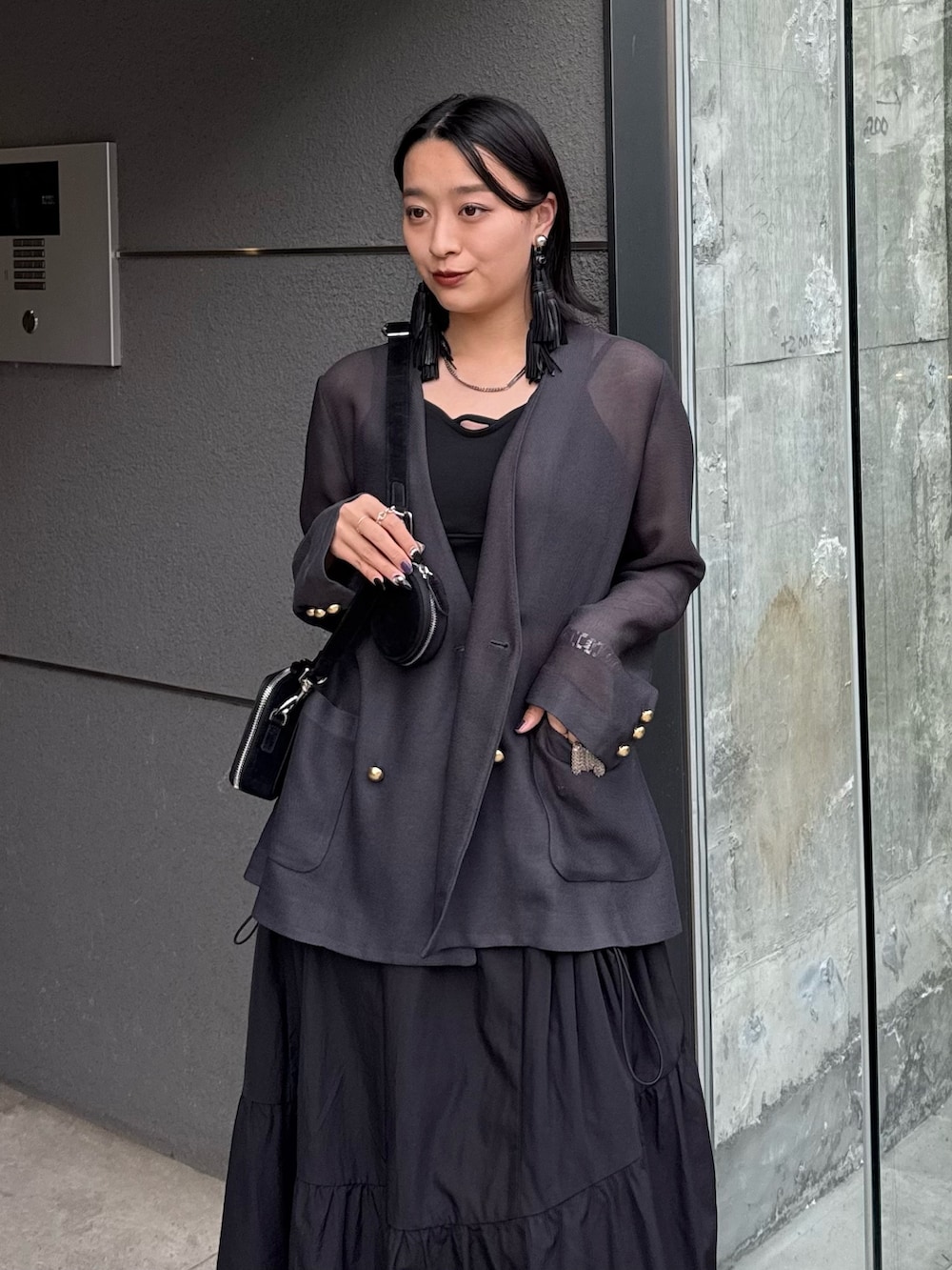 グレー系のテーラードジャケット、ブラック系のタンクトップ、ブラック系のスカートを着用したレディースの春コーディネートの4枚目の写真