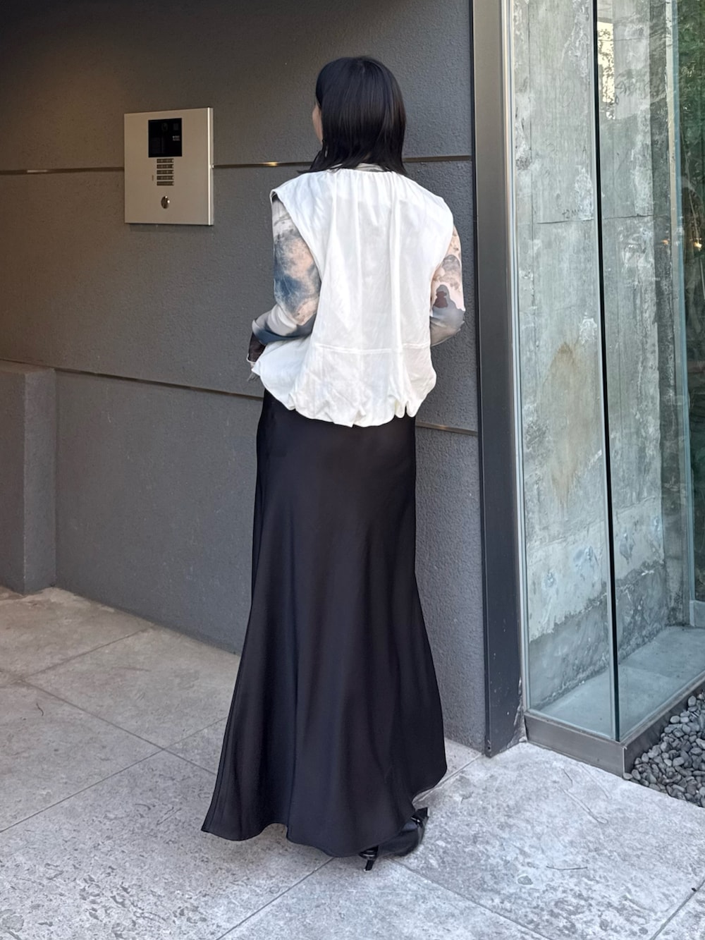 ホワイト系のベスト、グリーン系のTシャツ/カットソー、ブラック系のスカートを着用したレディースの春コーディネートの2枚目の写真