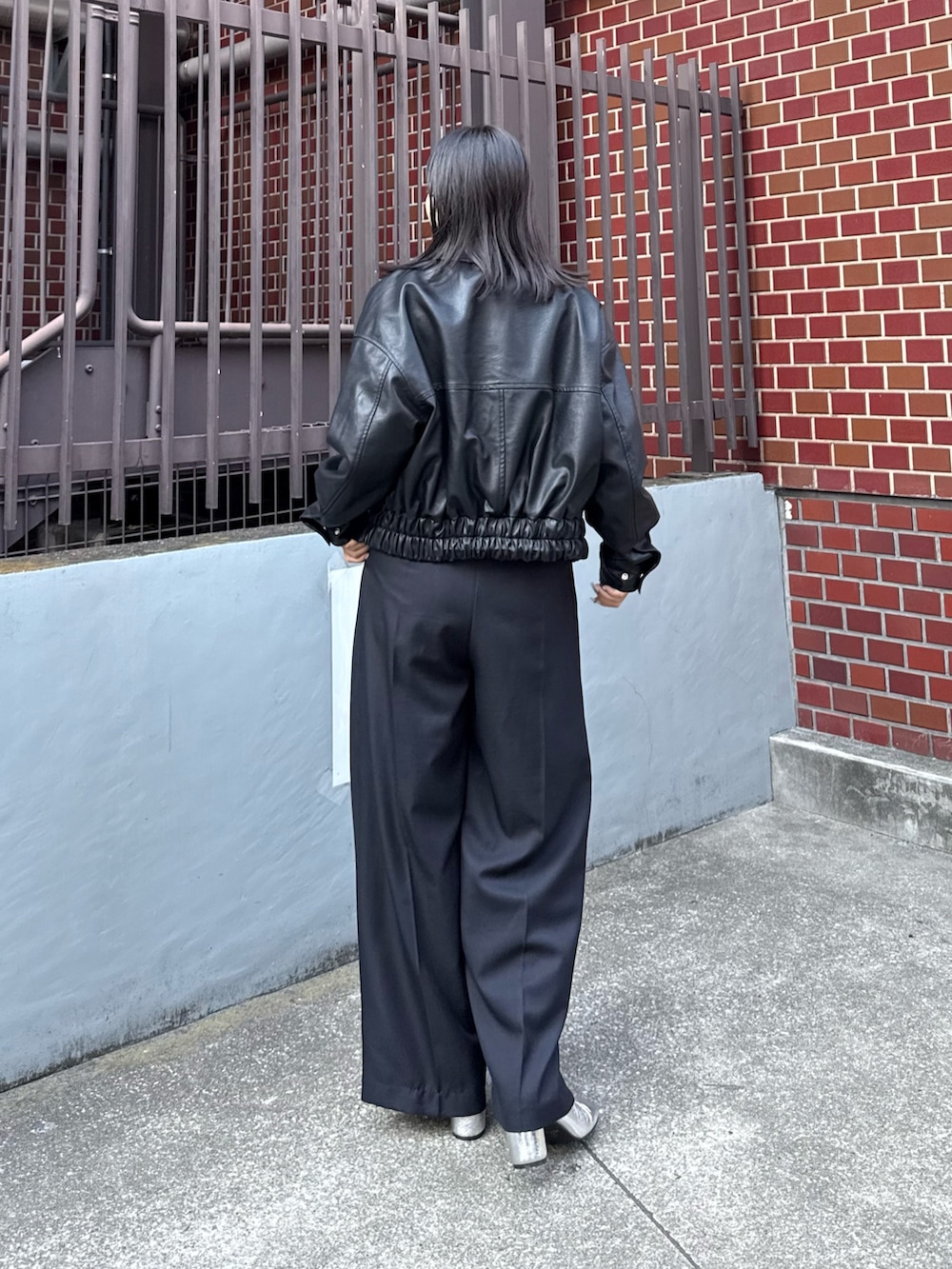 ブラック系のブルゾン、ベージュ系のニット/セーター、ブラック系のスラックスを着用したレディースの秋コーディネートの3枚目の写真