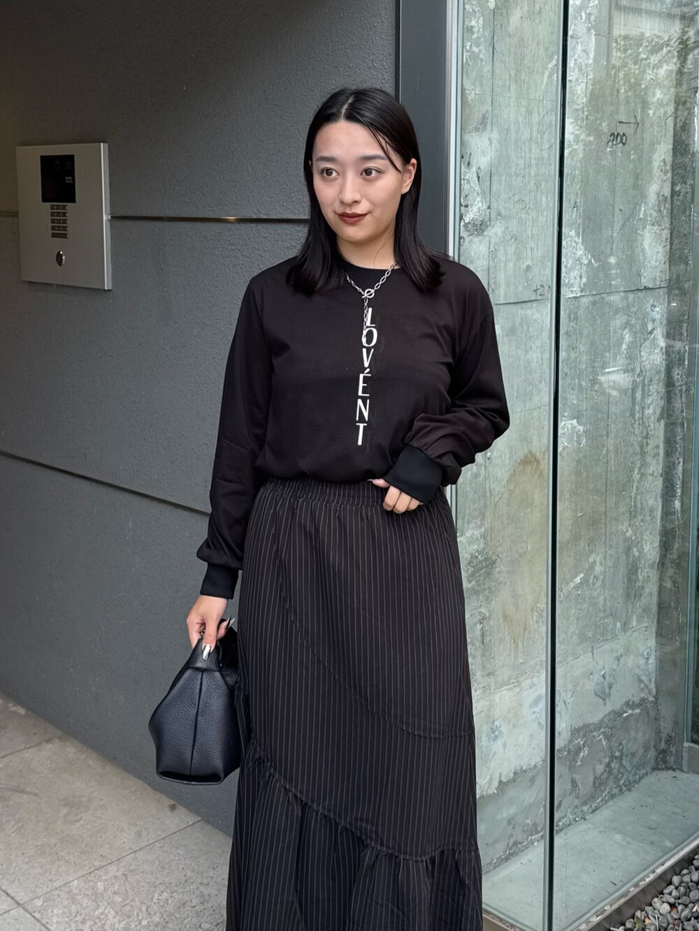 ブラック系のTシャツ/カットソー、ブラック系のスカート、ブラック系のトートバッグを着用したレディースの秋コーディネートの3枚目の写真