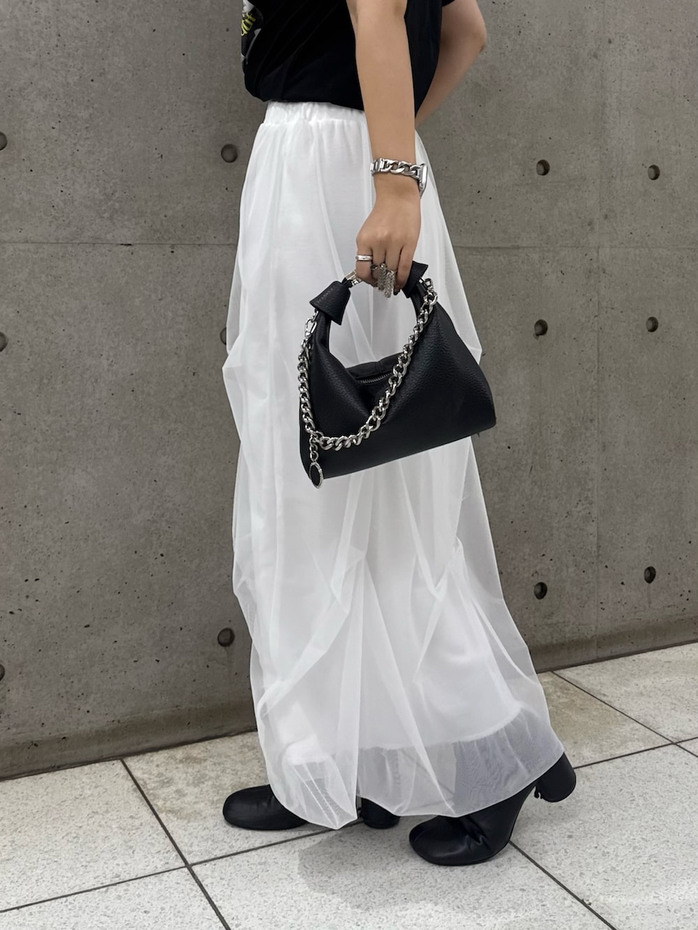 ブラック系のTシャツ/カットソー、ホワイト系のスカート、ブラック系のトートバッグを着用したレディースの春コーディネートの6枚目の写真