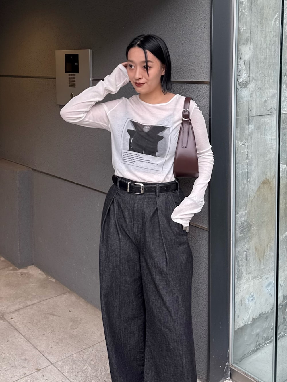 ブラック系のデニムパンツ、ホワイト系のTシャツ/カットソー、ブラウン系のハンドバッグを着用したレディースの秋コーディネートの3枚目の写真