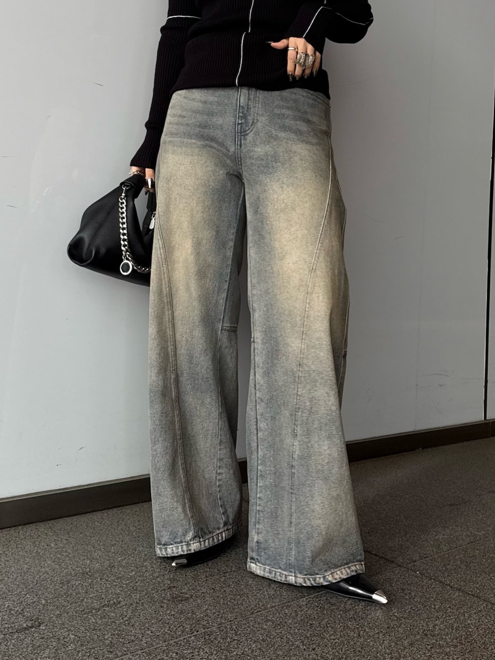 ブラック系のニット/セーター、ブルー系のデニムパンツ、ブラック系のトートバッグを着用したレディースの春コーディネートの5枚目の写真