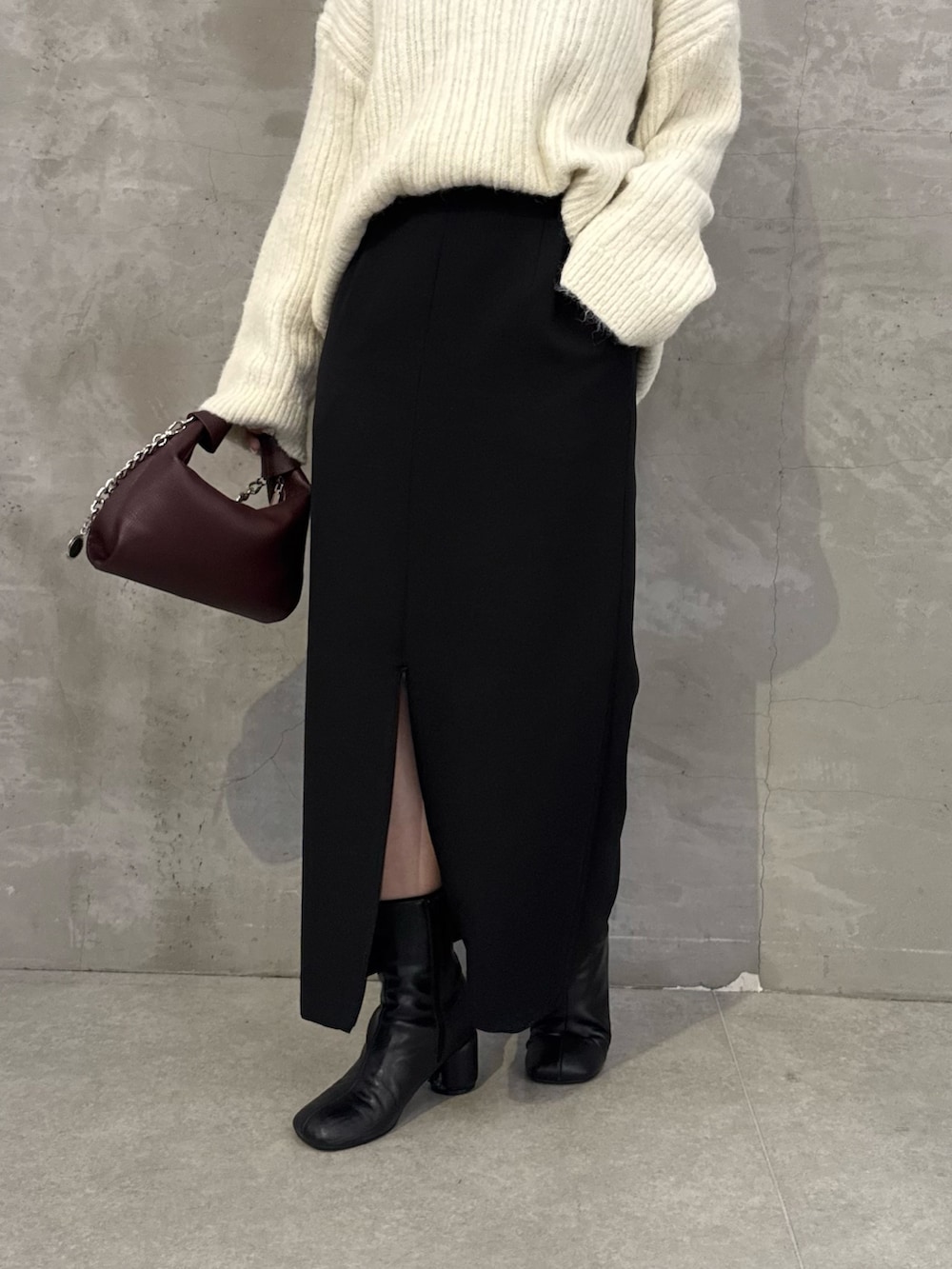 ホワイト系のニット/セーター、ブラック系のスカート、レッド系のトートバッグを着用したレディースの秋コーディネートの7枚目の写真