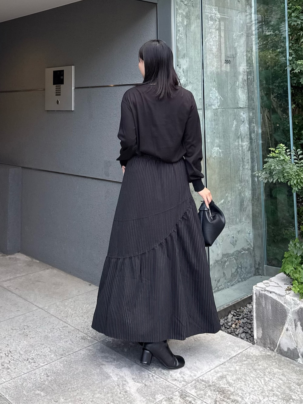 ブラック系のTシャツ/カットソー、ブラック系のスカート、ブラック系のトートバッグを着用したレディースの秋コーディネートの2枚目の写真