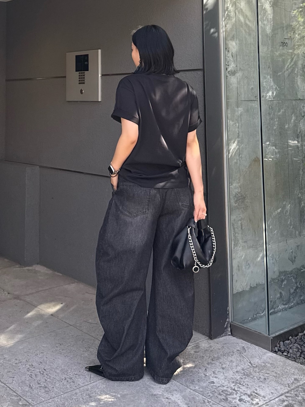 ブラック系のTシャツ/カットソー、ブラック系のデニムパンツ、ブラック系のトートバッグを着用したレディースの春コーディネートの3枚目の写真