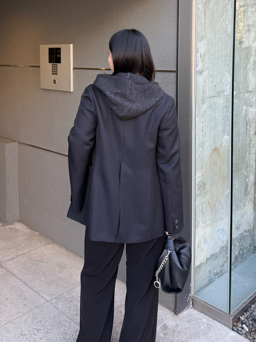 ブラック系のテーラードジャケット、ブラック系のニット/セーター、ブラック系のトートバッグを着用したレディースの冬コーディネートの5枚目の写真