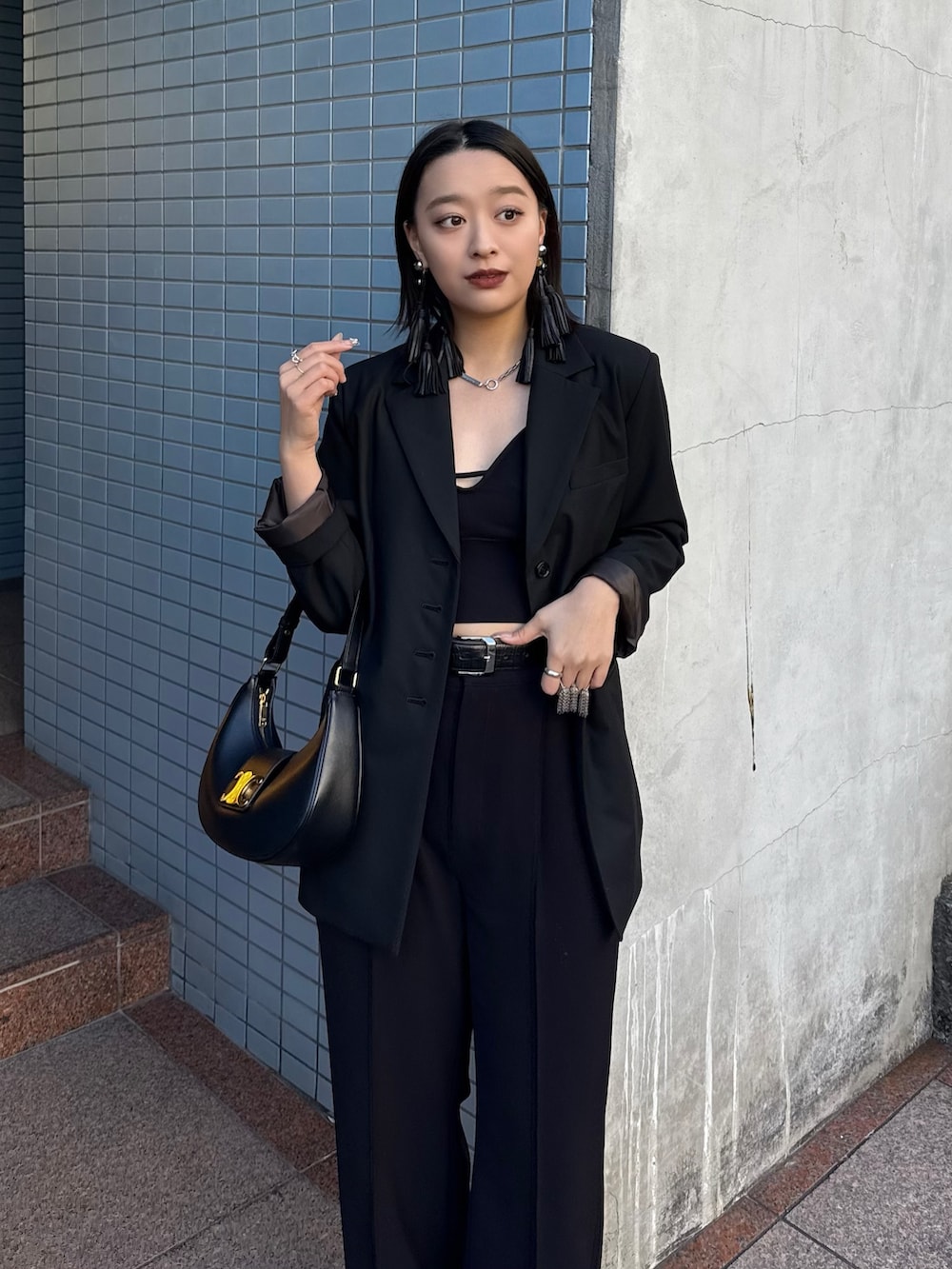 ブラック系のテーラードジャケット、ブラック系のスラックス、ブラック系のベルトを着用したレディースの冬コーディネートの4枚目の写真