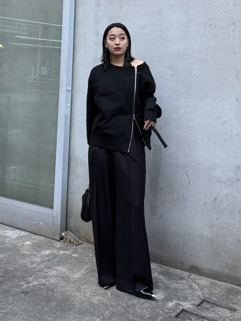 ブラック系のTシャツ/カットソー、ブラック系のスラックス、ブラック系のトートバッグを着用したレディースの冬コーディネートの2枚目の写真