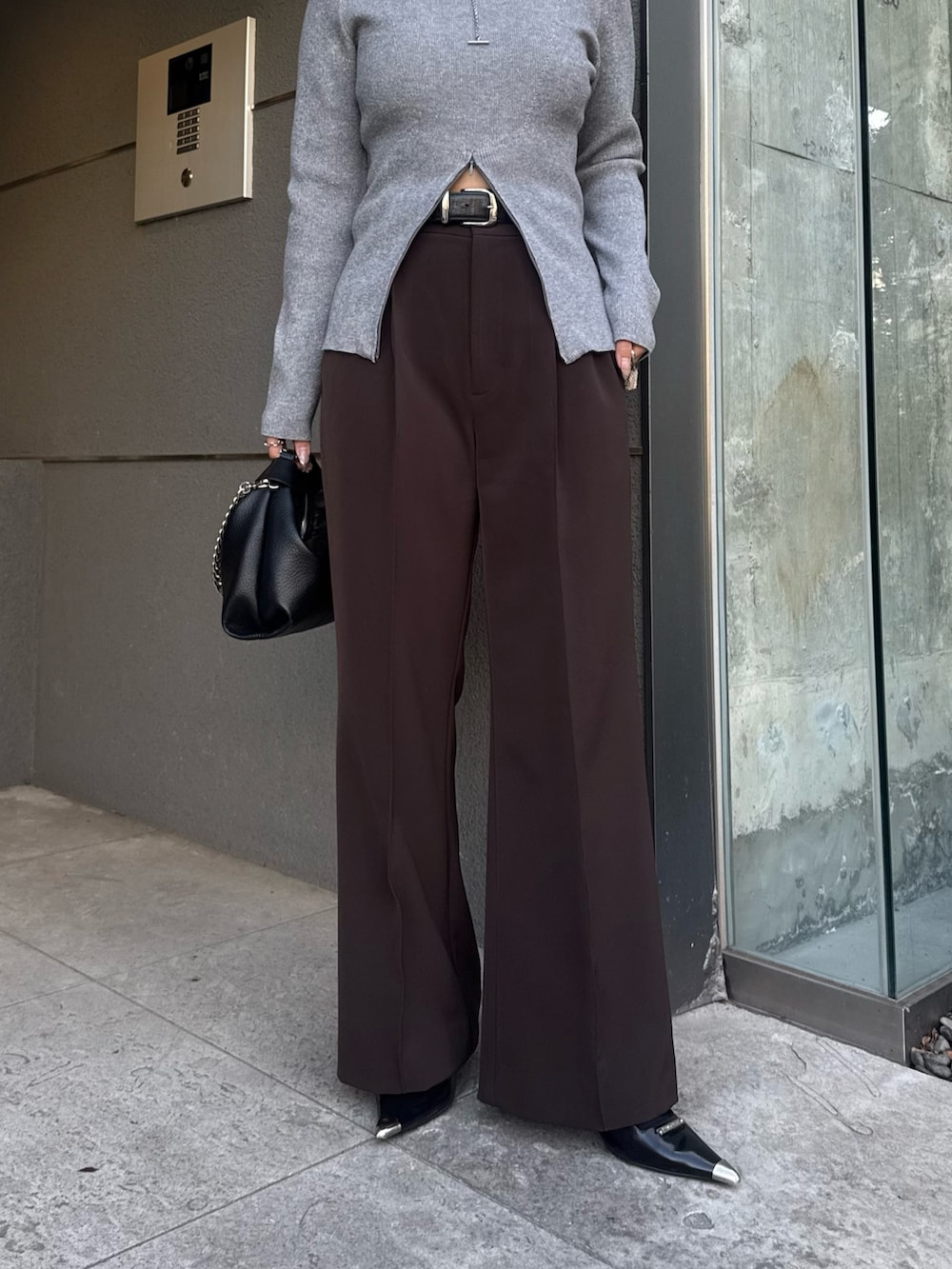 グレー系のニット/セーター、ブラウン系のスラックス、ブラック系のトートバッグを着用したレディースの冬コーディネートの5枚目の写真