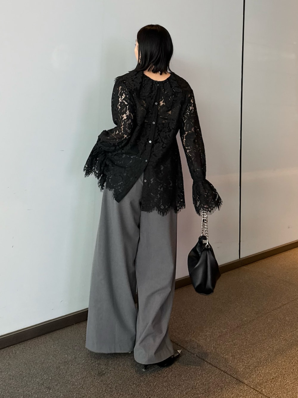 ブラック系のシャツ/ブラウス、グレー系のスラックス、ブラック系のトートバッグを着用したレディースの春コーディネートの2枚目の写真