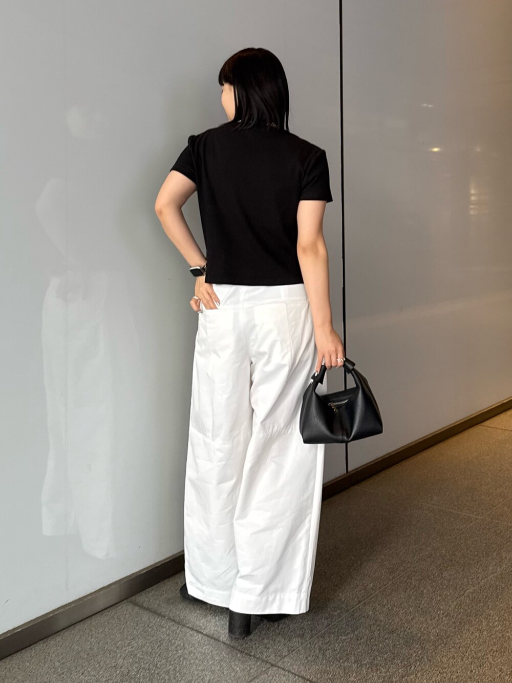 ブラック系のTシャツ/カットソー、ホワイト系のスラックス、ブラック系のショルダーバッグを着用したレディースの春コーディネートの3枚目の写真