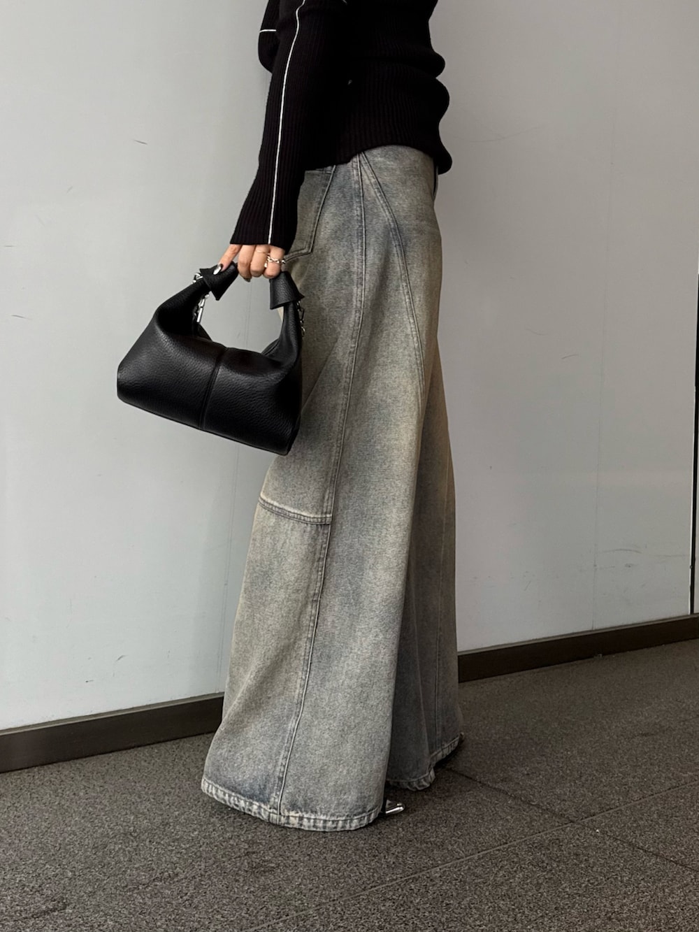 ブラック系のニット/セーター、ブルー系のデニムパンツ、ブラック系のトートバッグを着用したレディースの春コーディネートの6枚目の写真