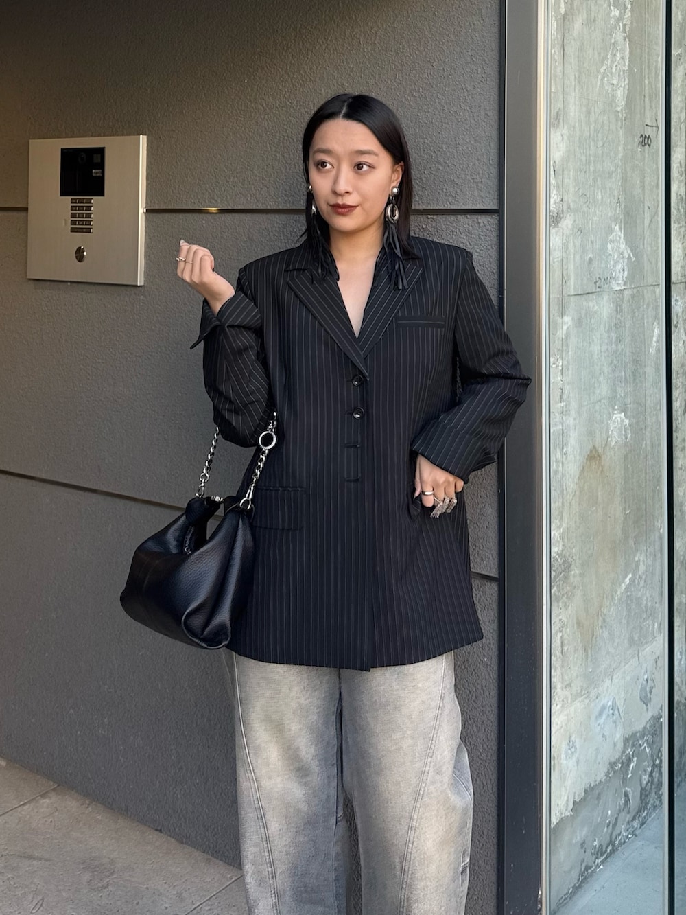 ブラック系のテーラードジャケット、ブルー系のデニムパンツ、ブラック系のトートバッグを着用したレディースの冬コーディネートの3枚目の写真