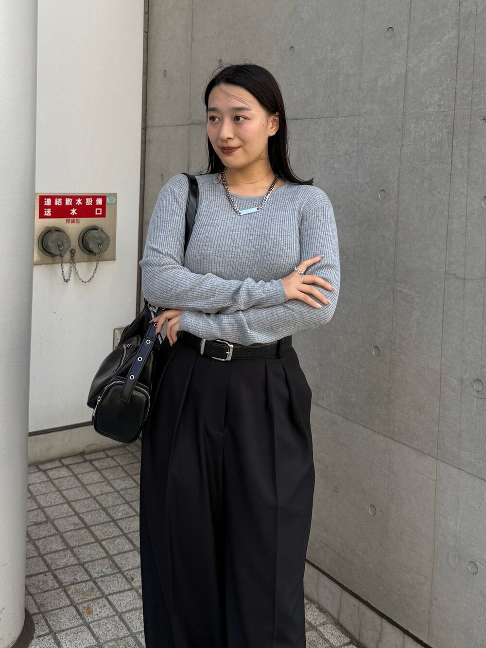 グレー系のニット/セーター、ブラック系のスラックス、ブラック系のショルダーバッグを着用したレディースの秋コーディネートの3枚目の写真