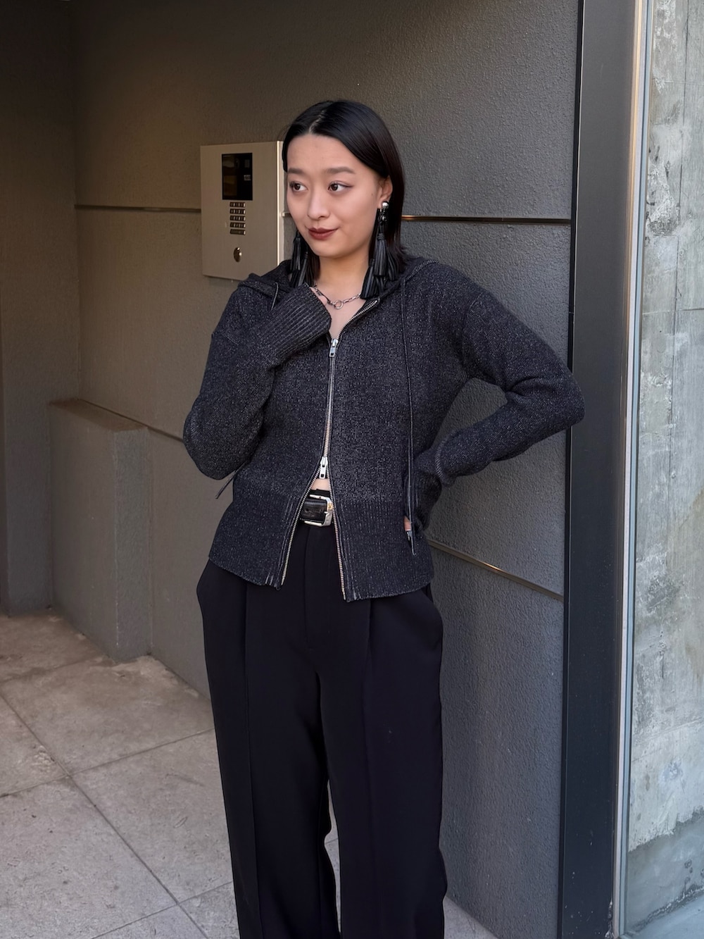 ブラック系のニット/セーター、ブラック系のスラックス、ブラック系のベルトを着用したレディースの冬コーディネートの3枚目の写真