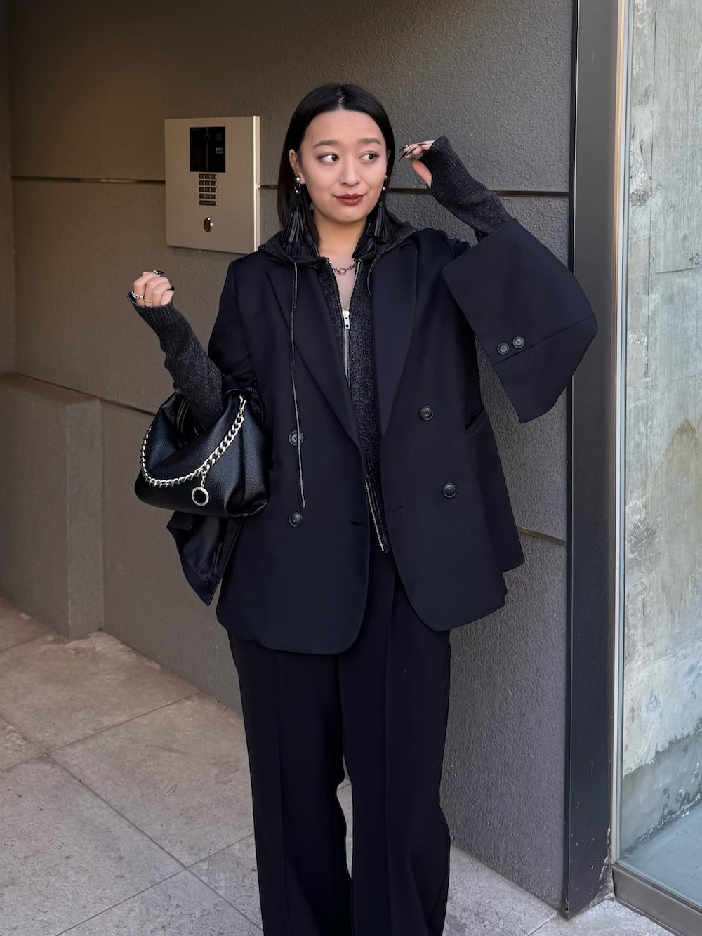 ブラック系のテーラードジャケット、ブラック系のニット/セーター、ブラック系のトートバッグを着用したレディースの冬コーディネートの4枚目の写真