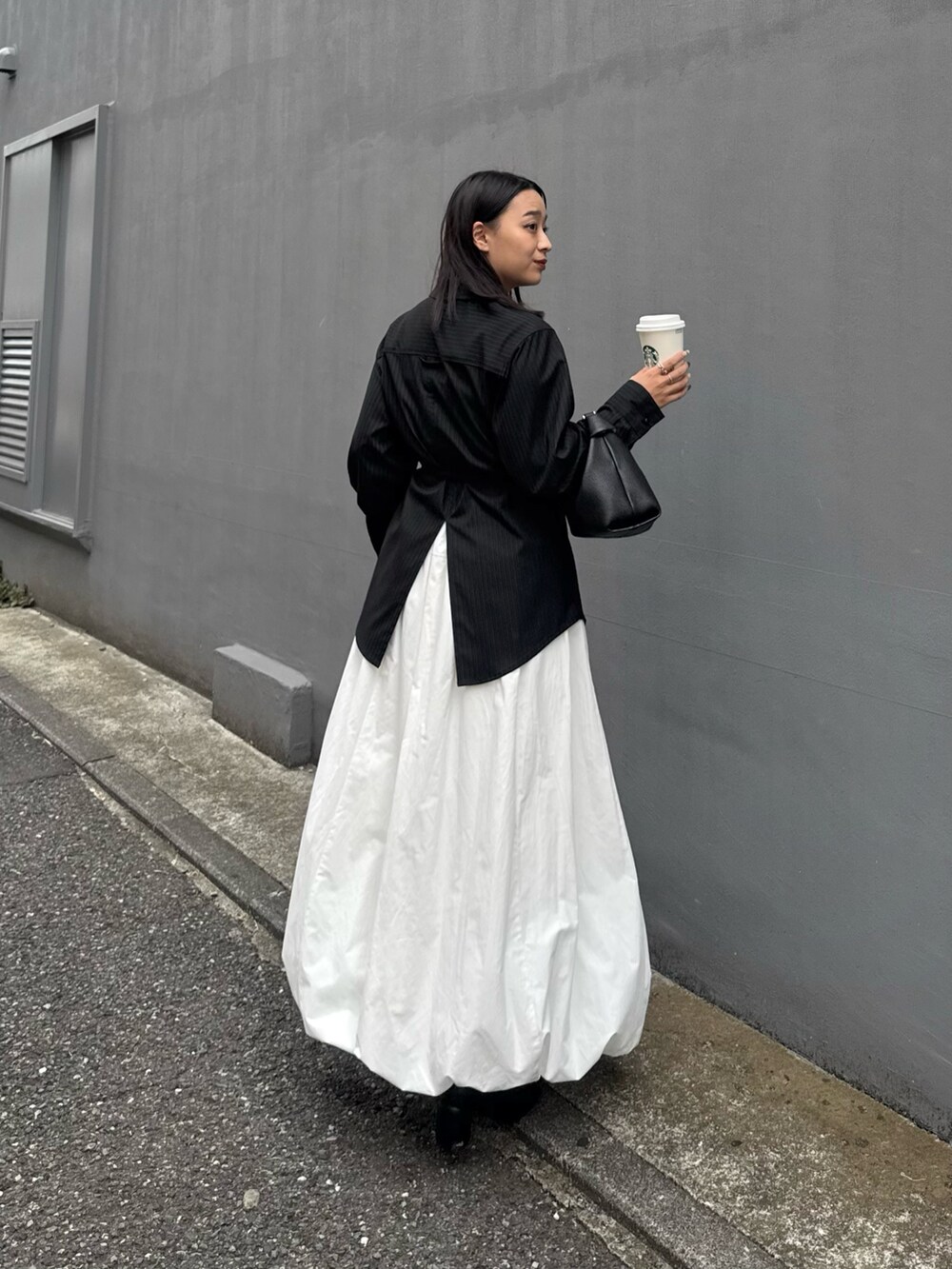 グレー系のシャツ/ブラウス、ホワイト系のスカート、ブラック系のトートバッグを着用したレディースの秋コーディネートの2枚目の写真