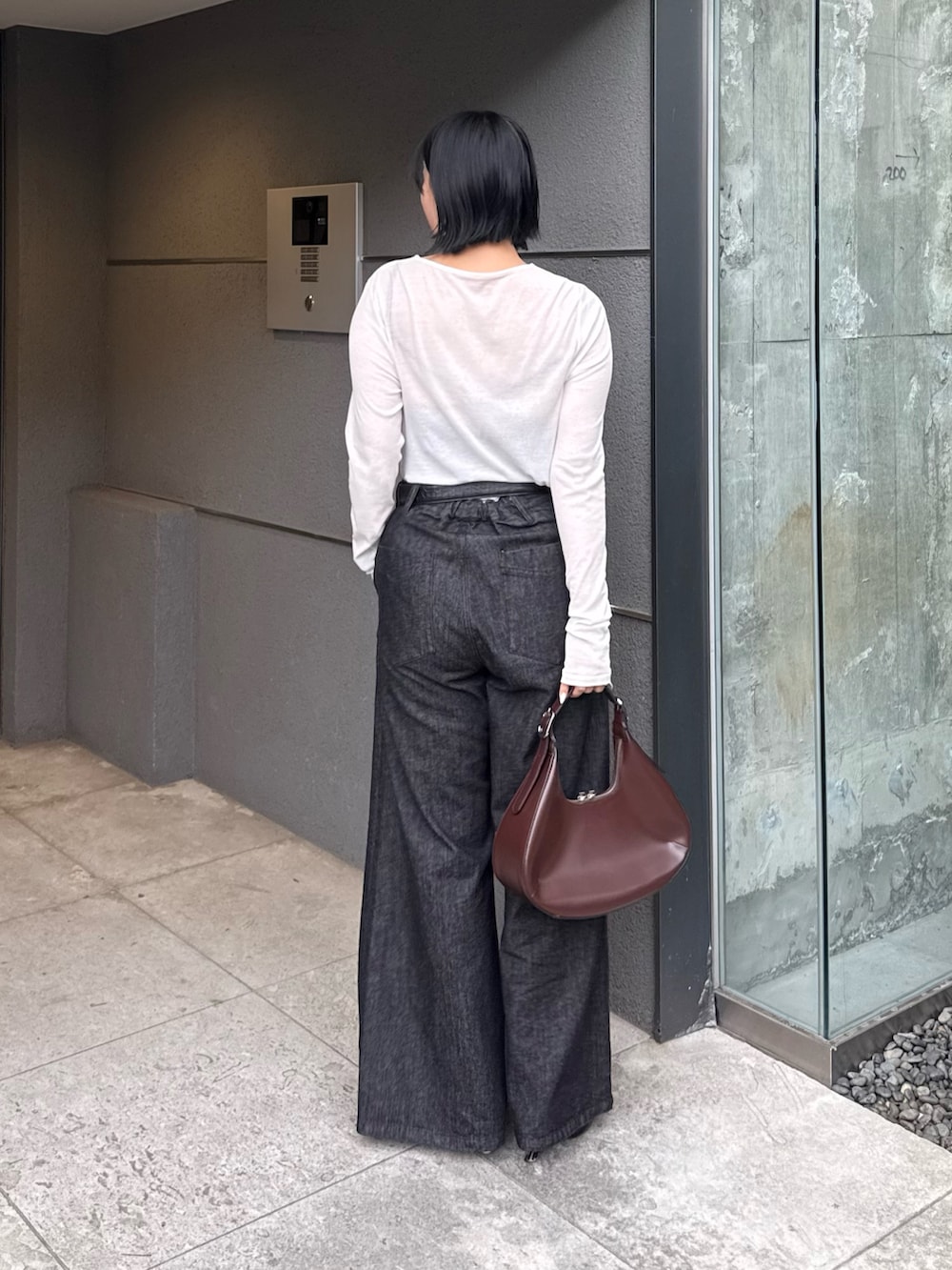 ブラック系のデニムパンツ、ホワイト系のTシャツ/カットソー、ブラウン系のハンドバッグを着用したレディースの秋コーディネートの2枚目の写真