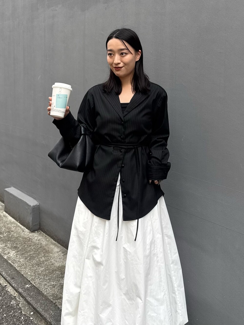 グレー系のシャツ/ブラウス、ホワイト系のスカート、ブラック系のトートバッグを着用したレディースの秋コーディネートの3枚目の写真