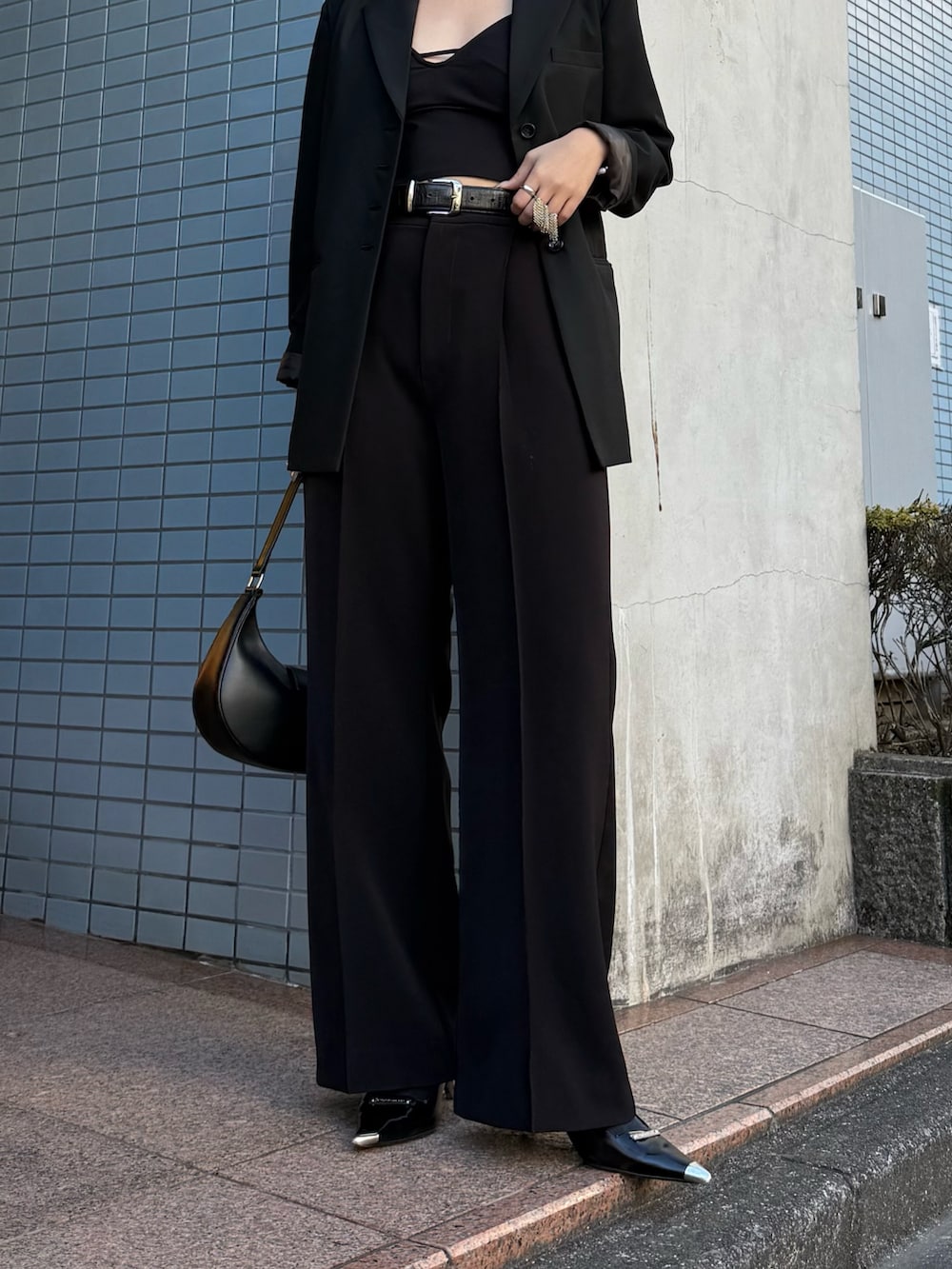 ブラック系のテーラードジャケット、ブラック系のスラックス、ブラック系のベルトを着用したレディースの冬コーディネートの3枚目の写真