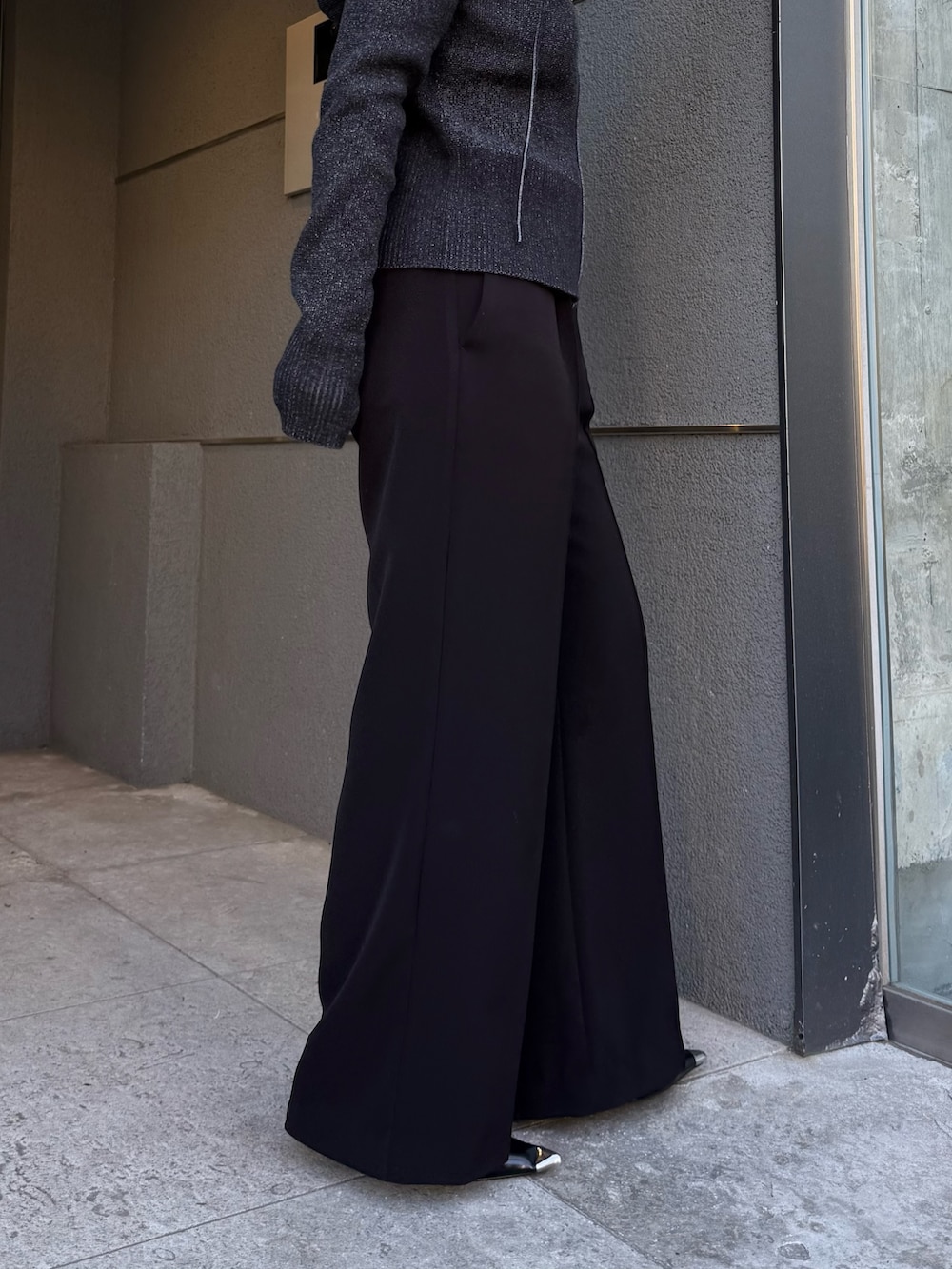 ブラック系のニット/セーター、ブラック系のスラックス、ブラック系のベルトを着用したレディースの冬コーディネートの6枚目の写真