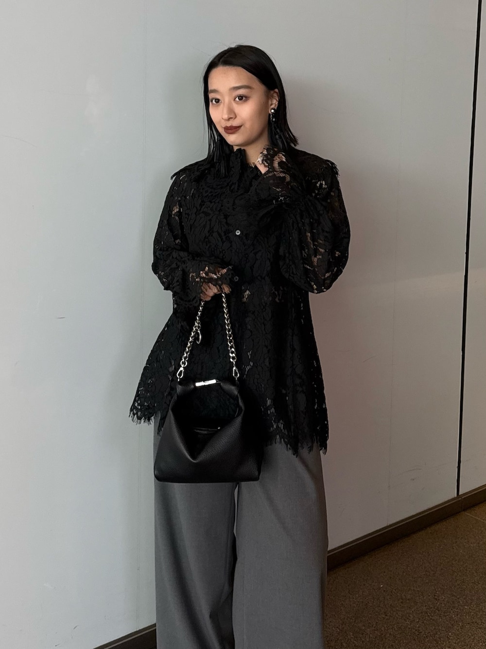 ブラック系のシャツ/ブラウス、グレー系のスラックス、ブラック系のトートバッグを着用したレディースの春コーディネートの3枚目の写真