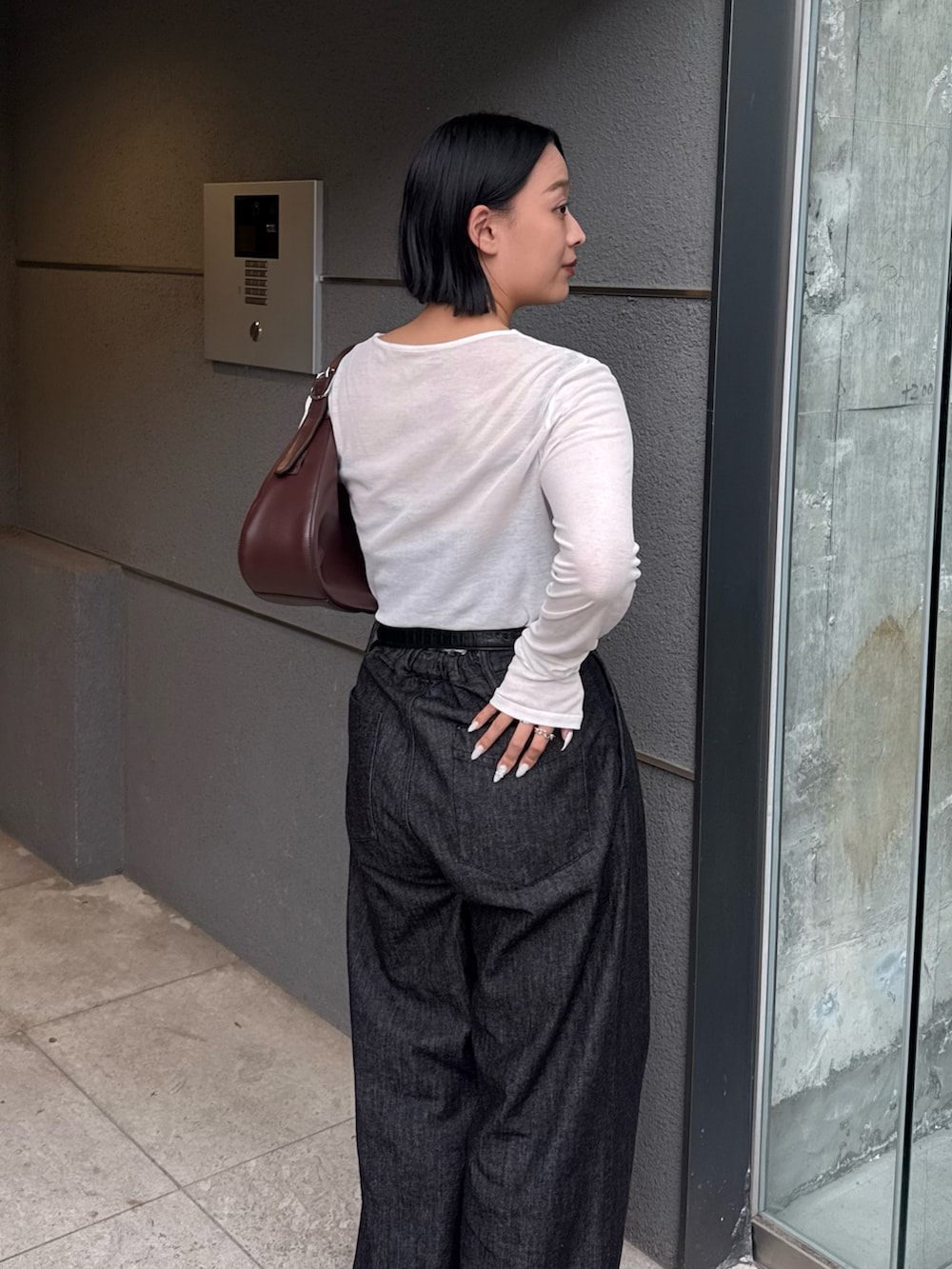 ブラック系のデニムパンツ、ホワイト系のTシャツ/カットソー、ブラウン系のハンドバッグを着用したレディースの秋コーディネートの4枚目の写真