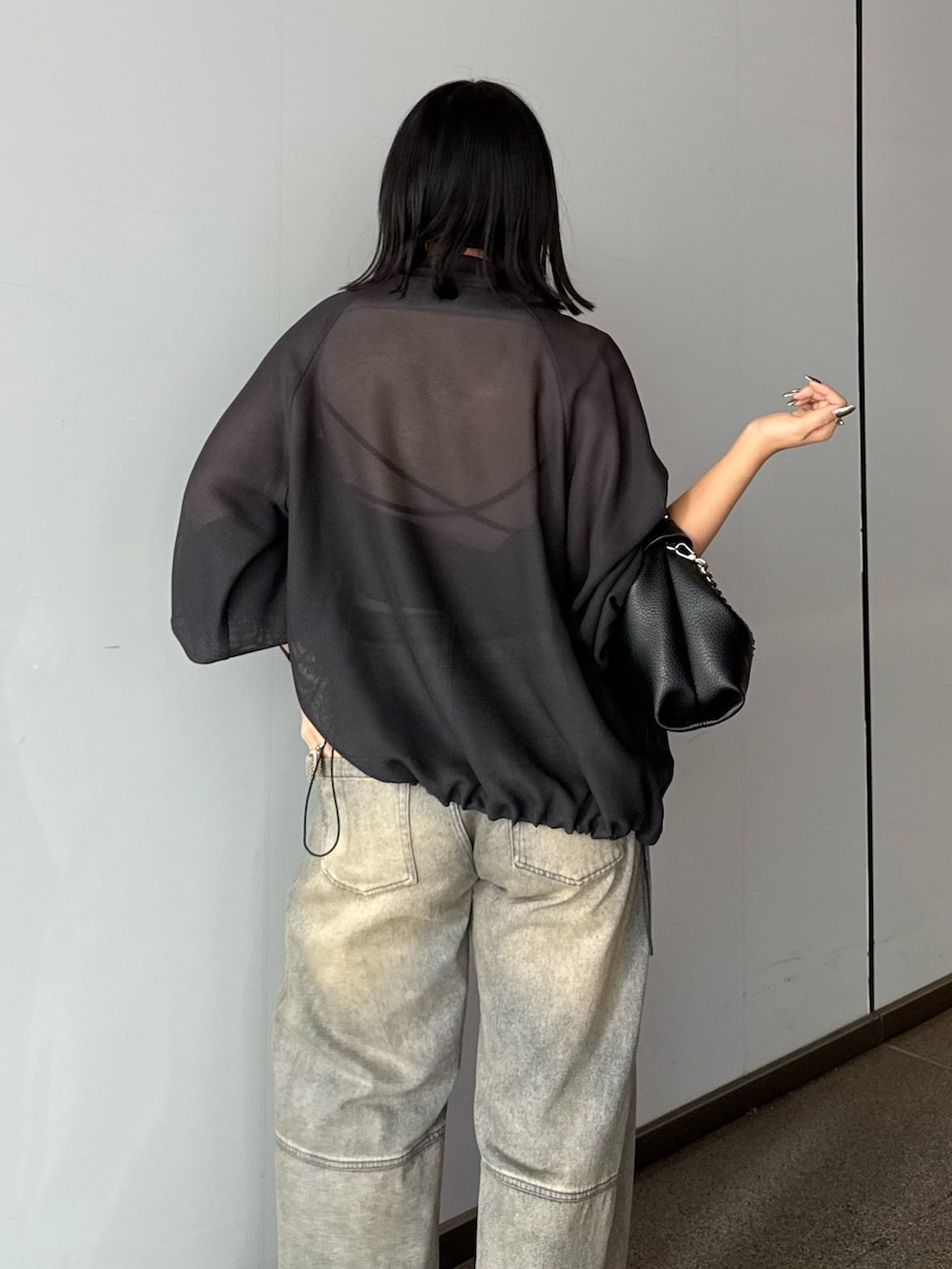 グレー系のブルゾン、ブルー系のデニムパンツ、ブラック系のトートバッグを着用したレディースの春コーディネートの4枚目の写真