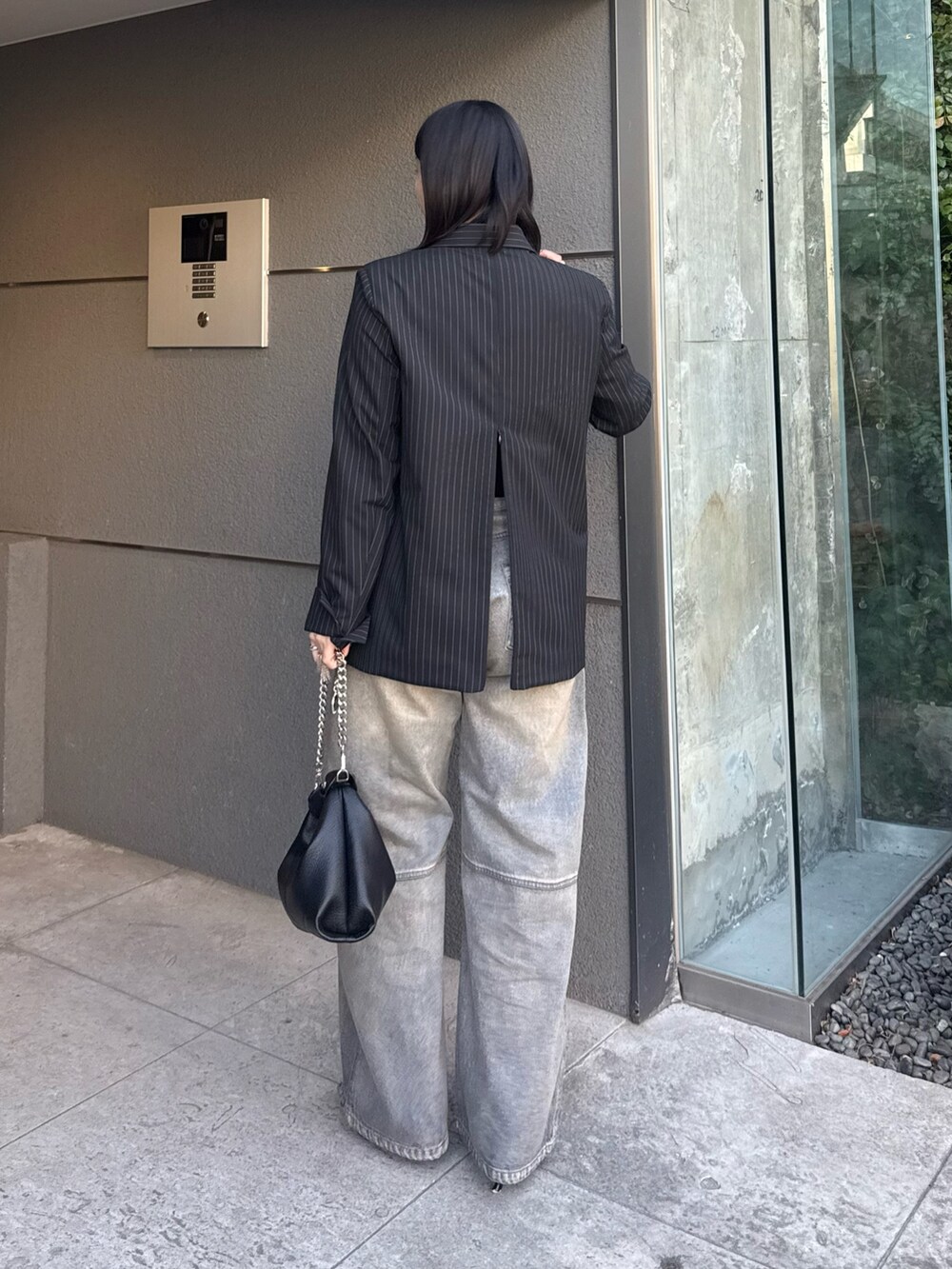 ブラック系のテーラードジャケット、ブルー系のデニムパンツ、ブラック系のトートバッグを着用したレディースの冬コーディネートの2枚目の写真