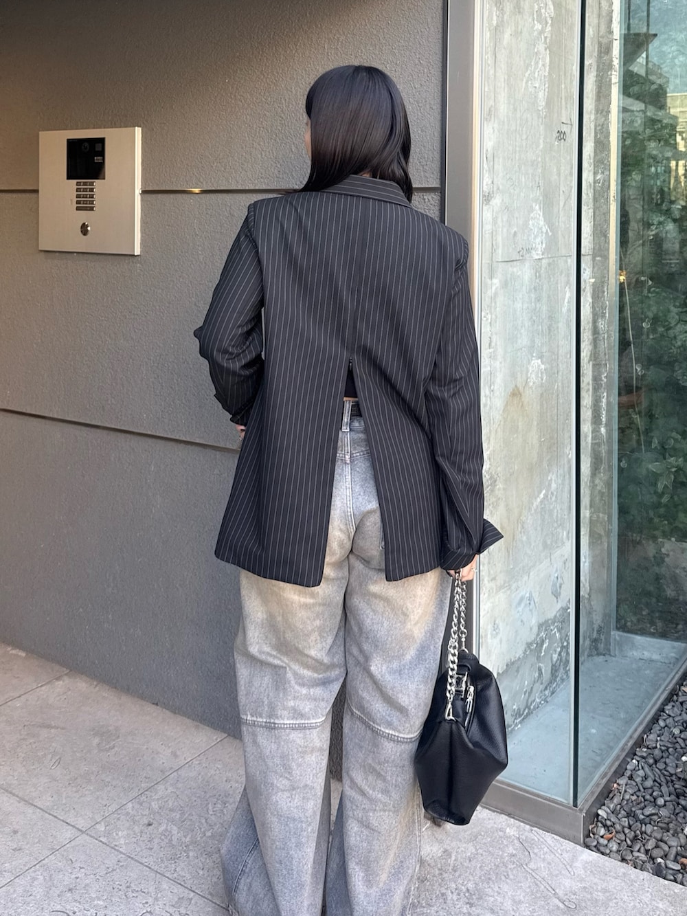 ブラック系のテーラードジャケット、ブルー系のデニムパンツ、ブラック系のトートバッグを着用したレディースの冬コーディネートの4枚目の写真