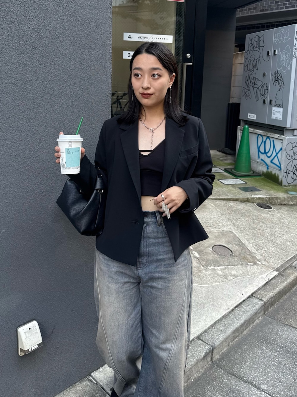 ブラック系のテーラードジャケット、ブラック系のブーツを着用したレディースの夏コーディネートの2枚目の写真