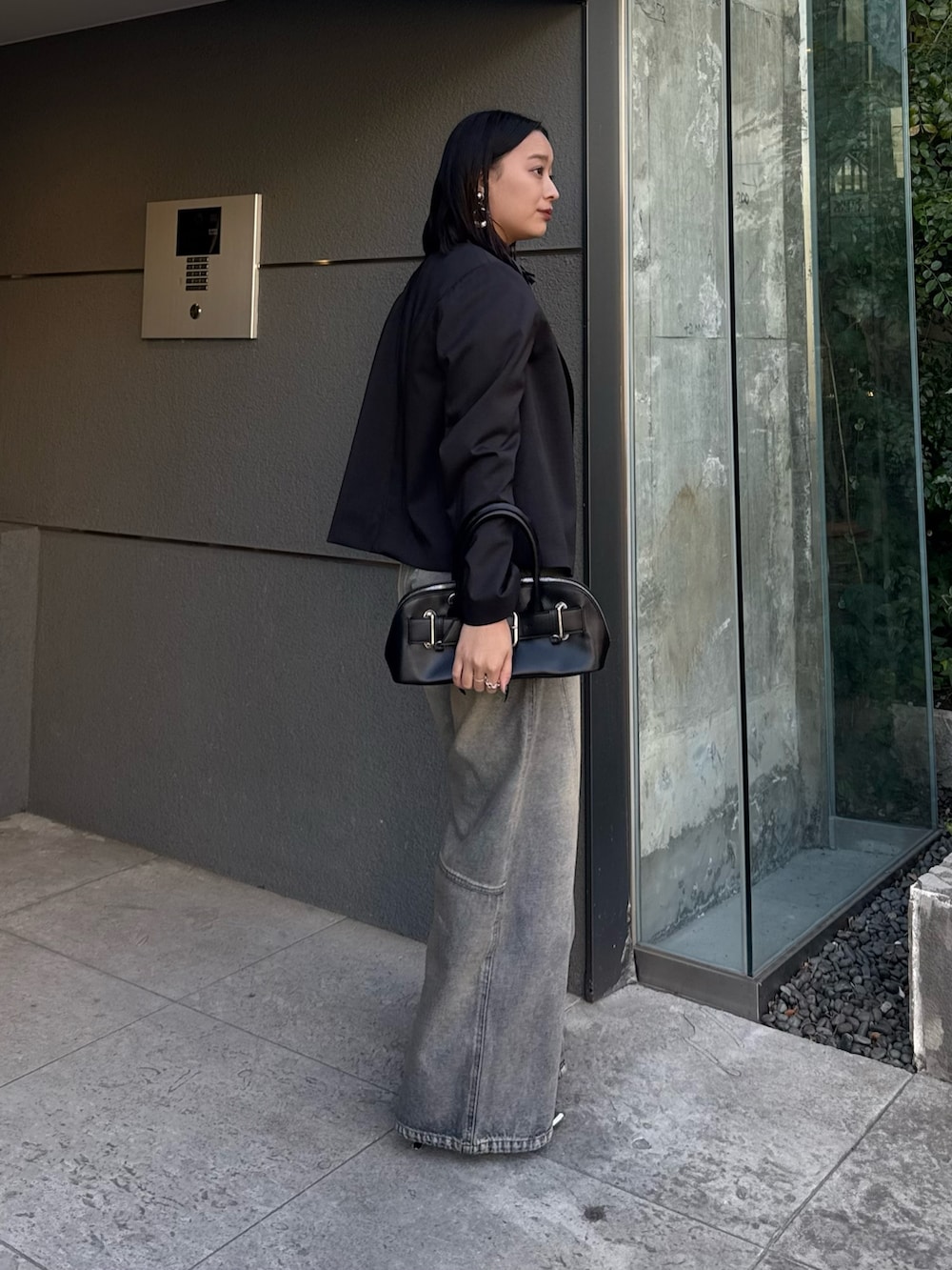 ブラック系のテーラードジャケット、ブルー系のデニムパンツ、ブラック系のショルダーバッグを着用したレディースの冬コーディネートの2枚目の写真